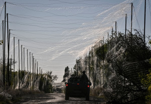 Ukrainian servicemen drive a vehicle on a road covered with anti-dronenets near the front line in Dnipropetrovsk region