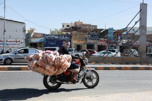 Man transports loaves of bread on a bike, in Sanaa