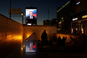 A screen displays an image of Russian President Vladimir Putin in Moscow