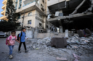 Palestinian children walk past the site of an Israeli strike on an apartment building in Gaza City