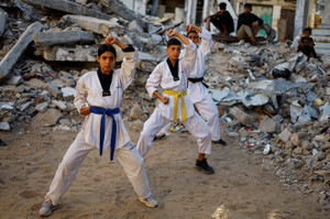 Palestinian youth train in taekwondo near a house destroyed during the war, in Nuseirat