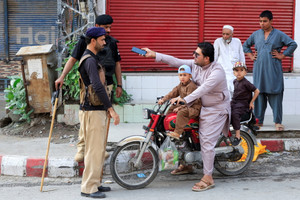 Police guard a road leading to the Red Zone, in Peshawar