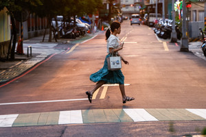 A woman crosses a street at a pedestrian crossing in New Taipei City