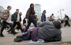 Pedestrians walk past a homeless person near Alexanderplatz square in Berlin